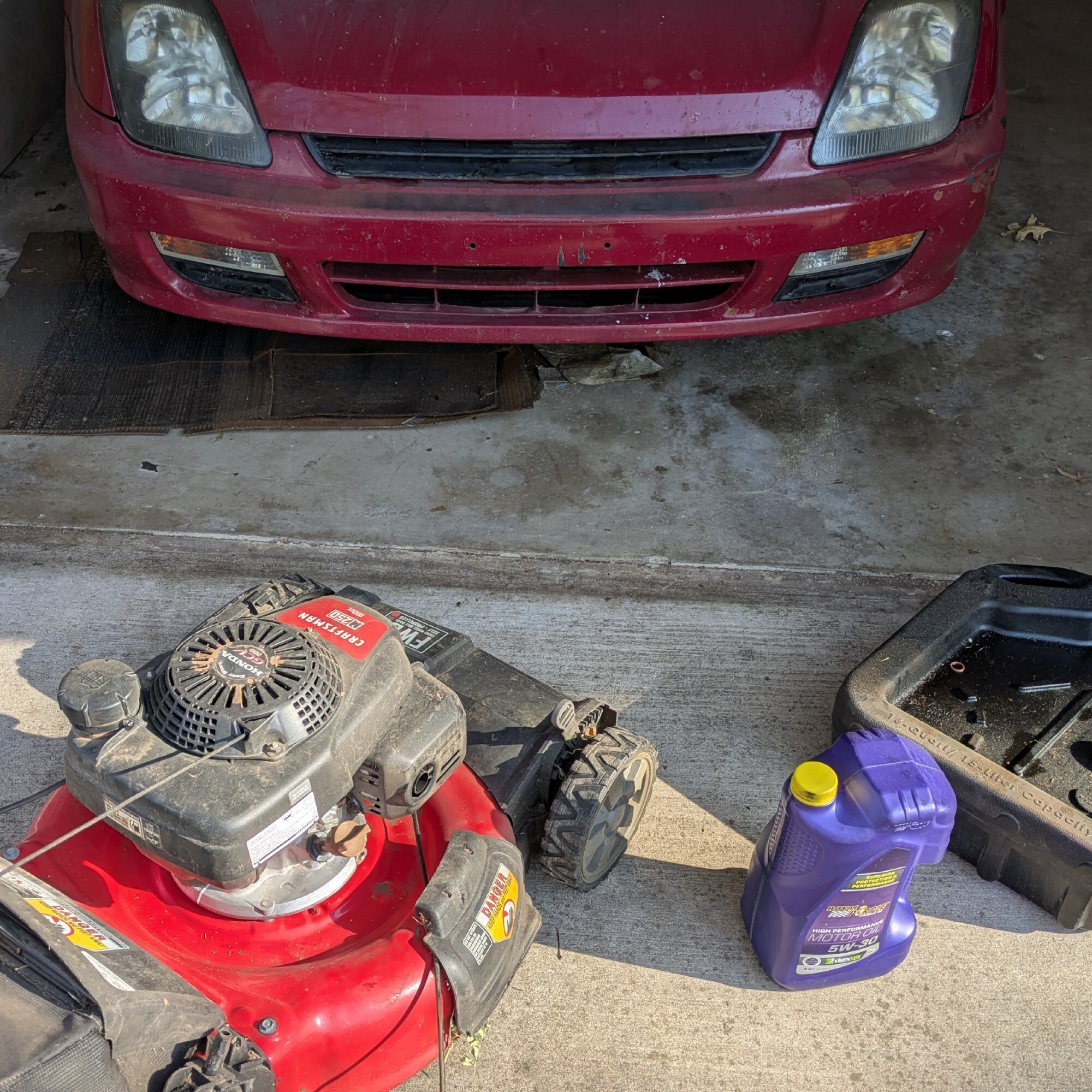 A 5 quart jug of Royal Purple engine oil sits next to a Craftsman push mower equipped with a Honda engine and an engine oil catch pan. In the background is a 5th generation Honda Prelude, a sports coupe from the late 90s.